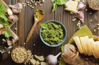 Flat lay view at food background with genovese pesto sauce and its ingredients on wooden kitchen