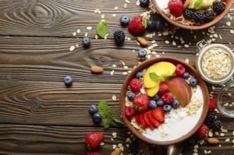 Flat lay of fruit healthy muesli with peaches strawberry almonds and blackberry in clay dish with