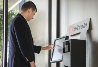 Young businessman buying cryptocurrency on ATM