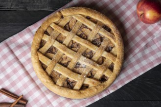 Above view of a delicious homemade apple pie with a lattice crust, on a pink towel, on a wooden