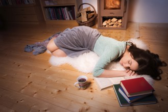 Evening image with a young beautiful woman that fell asleep while reading, on a white fur, in front