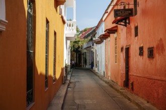 Narrow street in the old town of Cartagena with colorful one-story houses in sunlight and shadow,