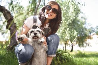 Happy caucasian woman in sunglasses resting in nature with her beloved dog schnauzer