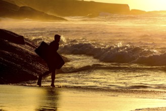 Bodyboarder going into the water at Ipanema tropical sunrise in Rio de Janeiro