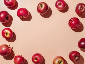 Red apples on orange or coral pink background with copy space for text or design in center.