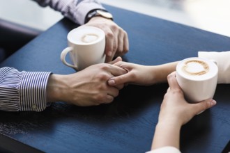 Hands on the table holding cups of coffee