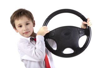 Funny little boy holding a car steering wheel. Young driver on a white background