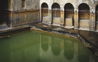 Water and buildings in an old roman bath in the city of Bath in the united kingdom england