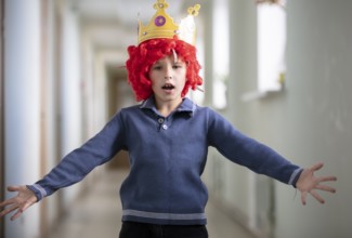 Child with a red wig and a crown. Clown boy