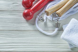 Skipping rope sweatbands dumbbells on wooden board fitness concept