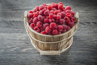 Raspberries in bucket on wooden board