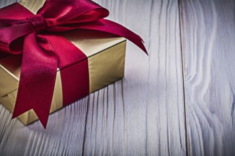 Present box with red ribbon on wooden board holidays concept