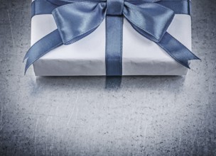 Present box with blue ribbon on metallic background celebrations concept