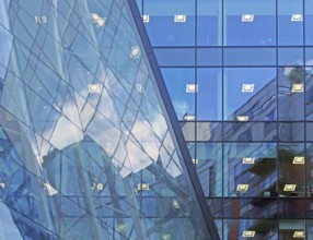 Blue sky and buildings reflected and mirrored in a large modern futuristic commercial office
