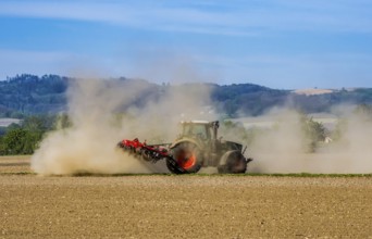 A farmer cultivates his parched field with a tractor during a dry period. Austria, Upper Austria,