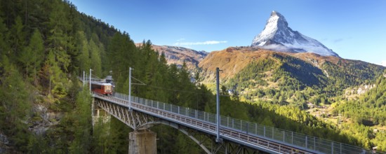 Zermatt, Switzerland. Gornergrat red tourist train on the bridge and Matterhorn peak panorama in