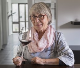 Senior citizen drinks wine at a table