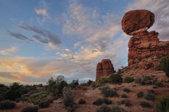 A colorful sunset glows over Balanced Rock, Arches National Park, Utah, USA, North America