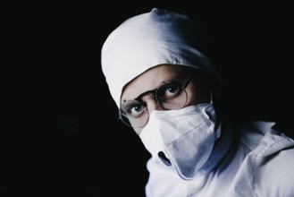 A medical professional wearing a mask and glasses in dark