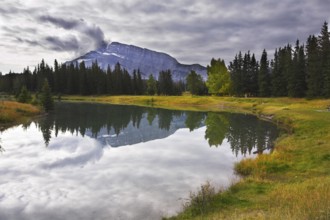 Lake in mountains surrounded by a wood and the cloudy sky