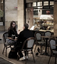 A young couple enjoy some baked goods on an outdoor patio in central Bordeaux, France, Europe