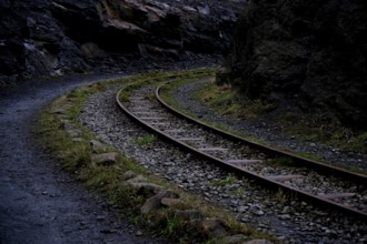 Abandoned railway line in a curve next to a narrow path through a rocky landscape, Piesberg 49134