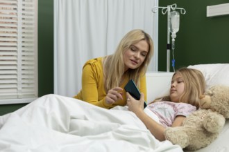 In a heartfelt hospital moment, a woman and a girl share a phone, reinforcing their connection in a