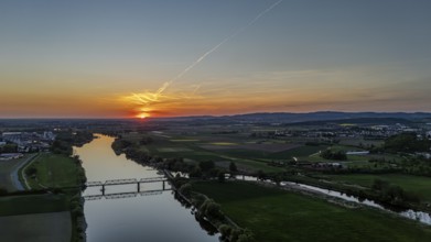 View of river and railway bridge in the light of a warm sunset, framed by fields, Danube, Bogen,