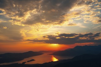 Orange clouds in the rays of the setting sun over the bay. View from Mount Lovcen.