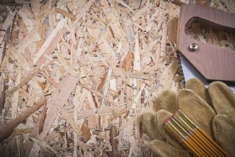 Protective leather gloves wooden meter handsaw on OSB