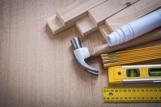 Wooden studs and meter ruler hammer blueprints construction level on wood background building and