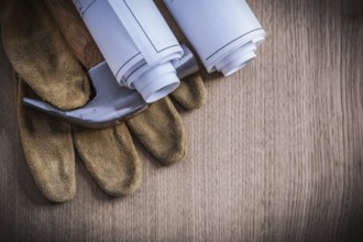 Construction drawings protective gloves and claw hammer on wooden board