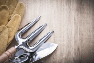 Steel trowel fork with shovel and leather safety gloves on wooden background copyspace image
