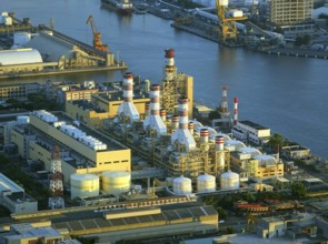 A large factory and industrial complex situated on the waterfront by the harbor