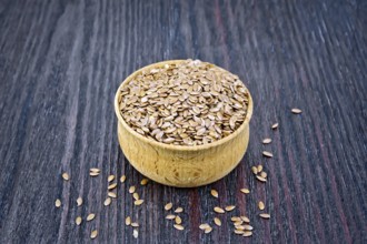 Seeds of linen brown in a bowl on the background of a wooden board