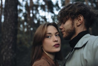 Close-up of a couple in an intimate pose outdoors with a forest background