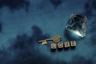 Ornamental key and fake diamond beside love wording with metal letters