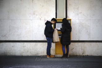 Frankfurt, Germany - January 05, 2017: Two young Asian tourists stand at a stamp vending machine at