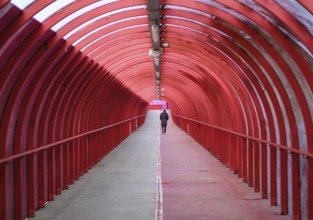 A Man Walking Alone Through A Covered Walkway At An Airport Or Train Station
