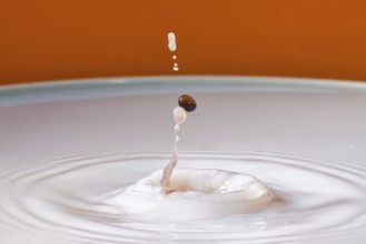 A drop with a splash in an orange environment creates dynamic fluid movement, water droplets,