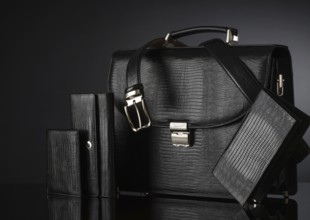 Fashionable men's set of leather accessories on a dark background. Briefcase, wallet, belt