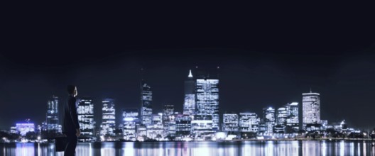 Elegant businessman with suitcase looking at night city