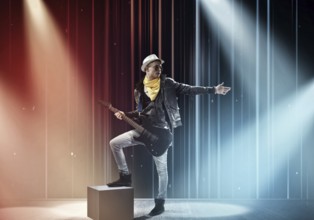 Young man rock musician in lights of stage