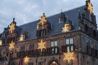 Old building with Christmas decorations and stars on the roof under a cloudy sky, nijmegen, the