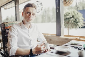Man enjoying a cup of coffee on a patio, ambient light surrounding him
