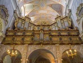 Lavishly decorated organ in a baroque church with detailed ceiling decorations and majestic
