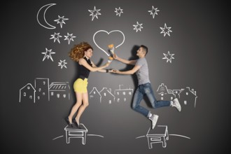 Happy valentines love story concept of a romantic couple standing on a stool and painting a heart
