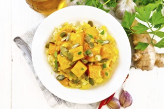 Millet porridge with spicy pumpkin sauce and seeds in a plate on a towel, hot pepper, ginger root,
