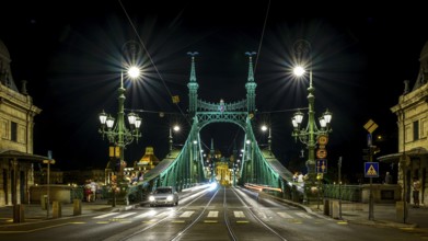 An illuminated bridge at night, cars driving towards the horizon, Budapest, Hungary, Europe
