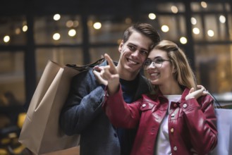 Beautiful couple with shopping bags is talking and smiling while doing shopping in the mall focus